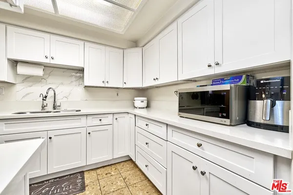 a kitchen with white cabinets and appliances