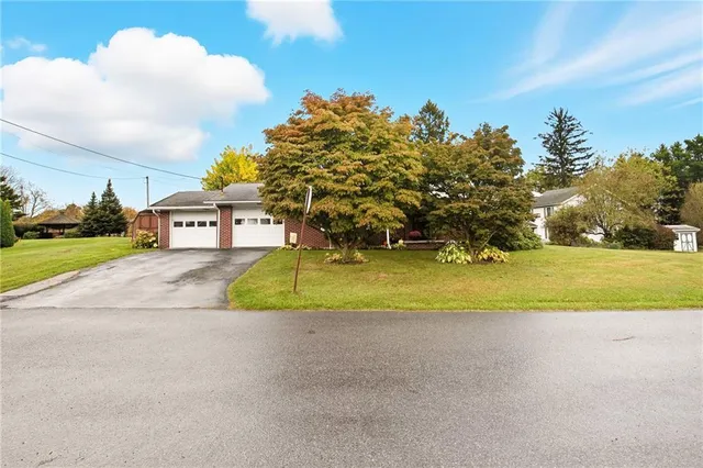 a view of a house with a big yard and large trees