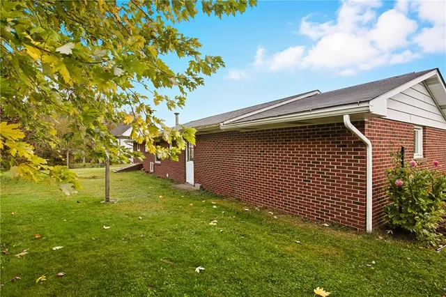a backyard of a house with plants and large tree
