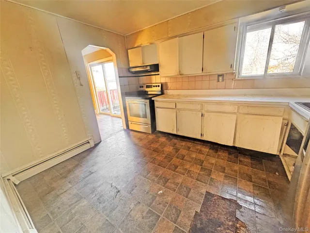a kitchen with a sink a stove cabinets and a window