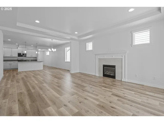 a view of an empty room with wooden floor and a fireplace