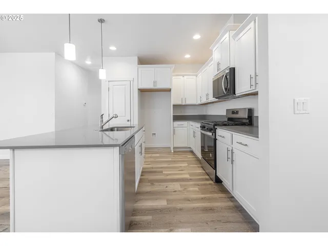 a kitchen with stainless steel appliances granite countertop a sink a stove and a refrigerator