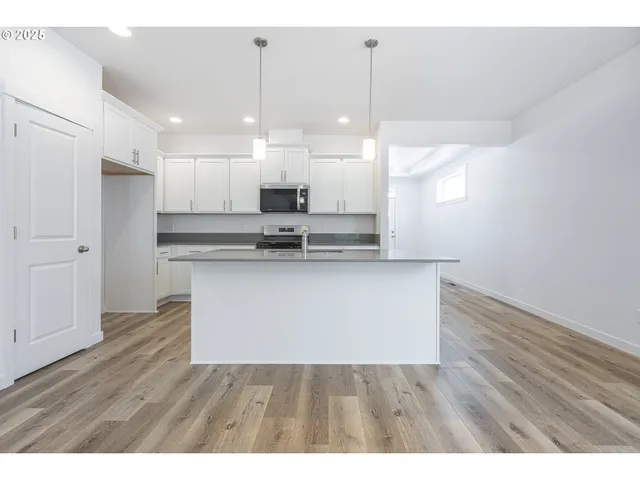 a view of kitchen with refrigerator stove and wooden floor