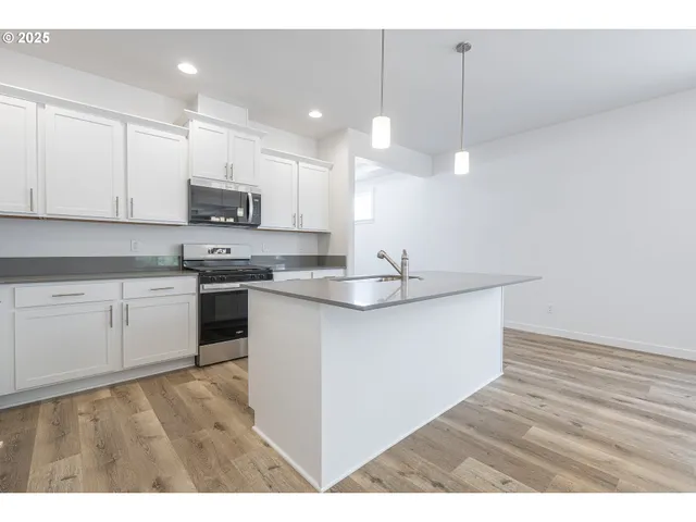 a kitchen with kitchen island granite countertop a sink counter top space appliances and cabinets