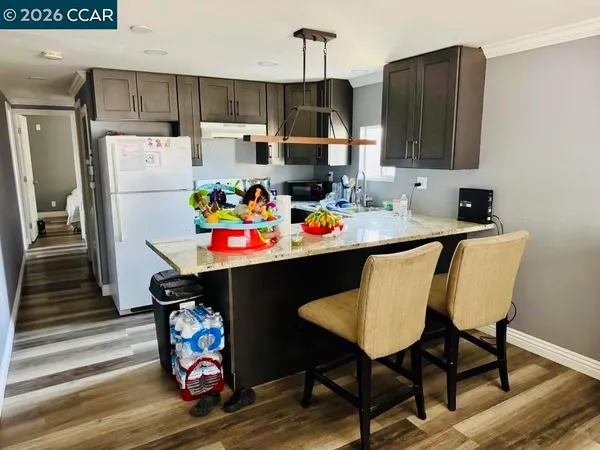 a kitchen with stainless steel appliances a dining table chairs refrigerator and sink