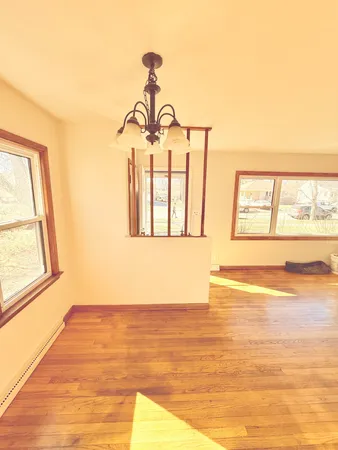 a view of an empty room with wooden floor and windows