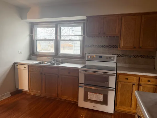 a kitchen with granite countertop wooden cabinets appliances and a sink
