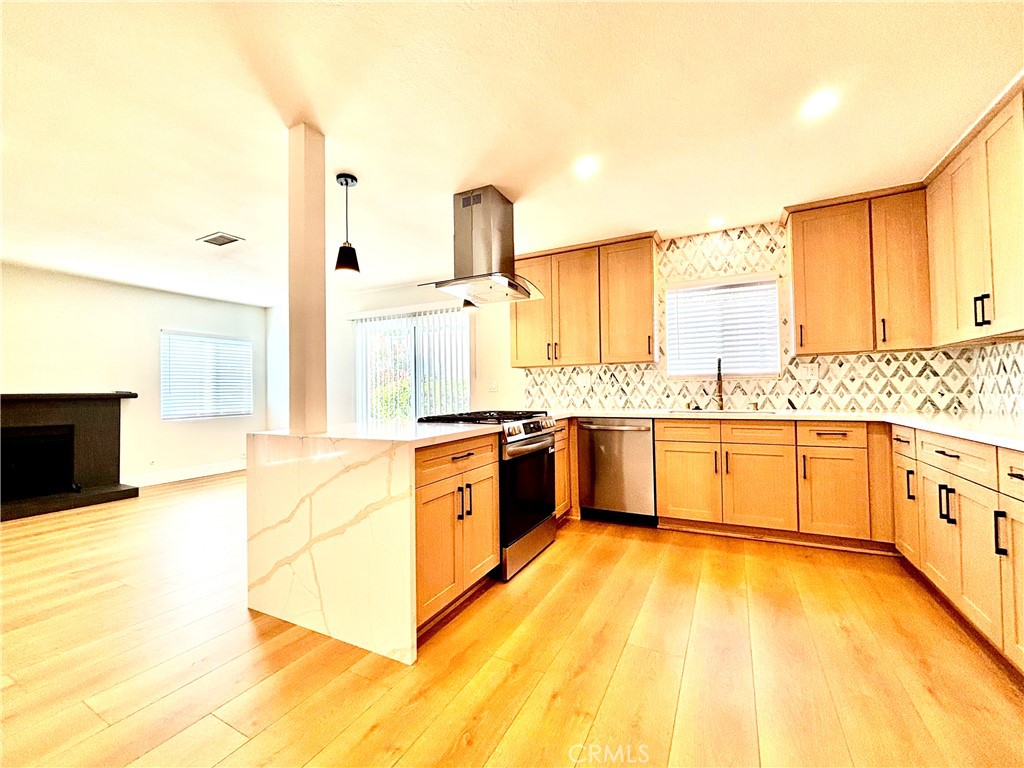 6210 Halstead Avenue, Unit A Rancho Cucamonga, CA 91701 - Photo 24 of 32 a large white kitchen with granite countertop a stove a sink and white cabinets with wooden floor