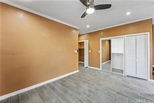 an empty room with closet and a ceiling fan