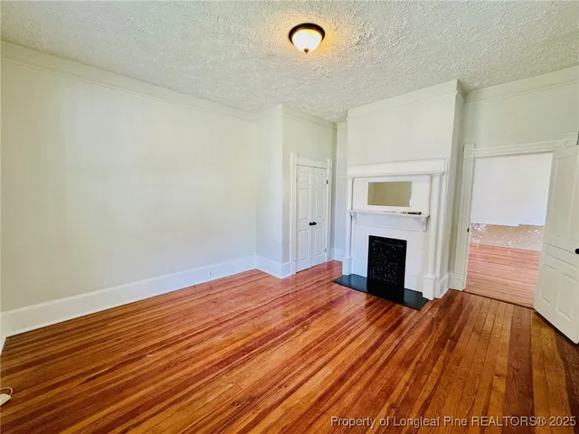 a view of empty room with wooden floor and fireplace