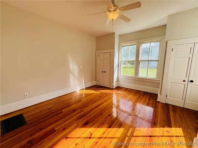 a view of an empty room with window and wooden floor