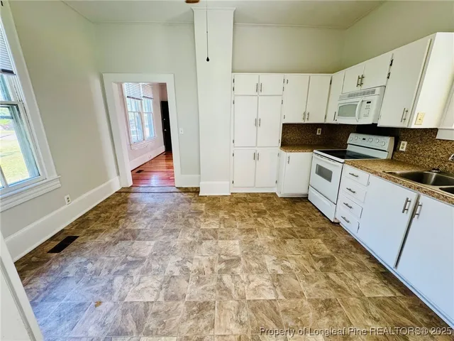 a kitchen with granite countertop white cabinets and white appliances