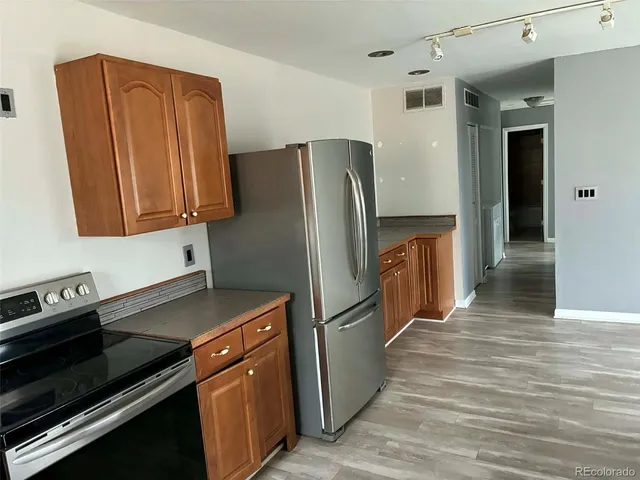 a kitchen with granite countertop a refrigerator and a stove top oven