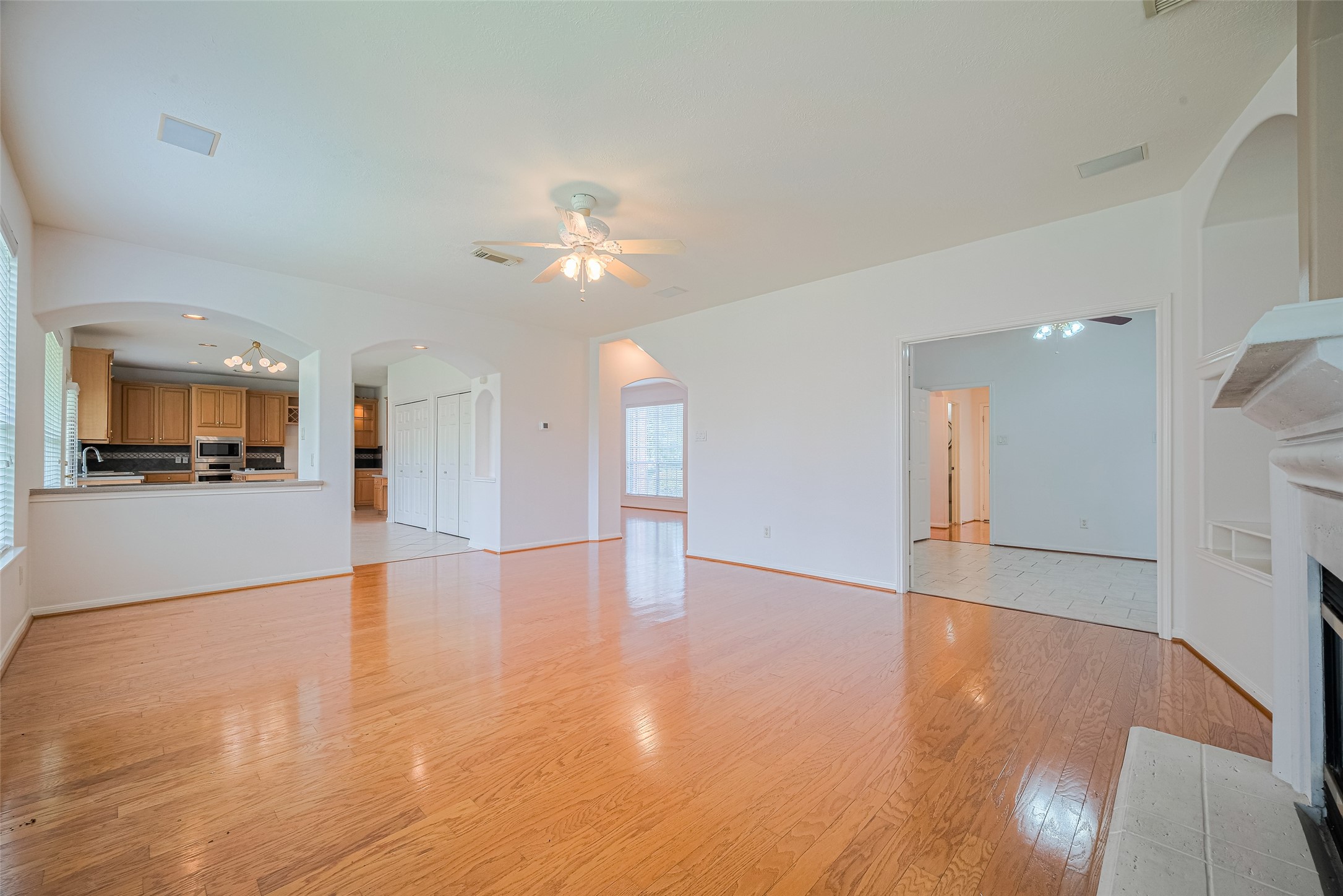 9218 Memorial Pines Way Spring, TX 77379 - Photo 11 of 39 This spacious family area features engineered wood floors, a ceiling fan, and abundant natural light. It opens to the kitchen with a breakfast bar and arched entryways, and has a cozy fireplace for added charm.