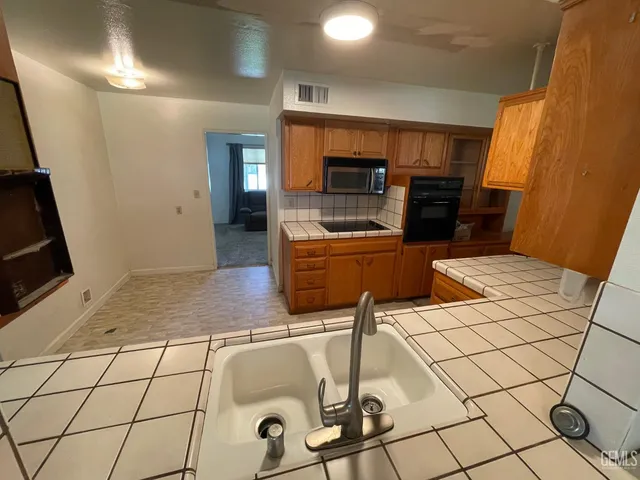 a living room with stainless steel appliances furniture a rug and a view of kitchen