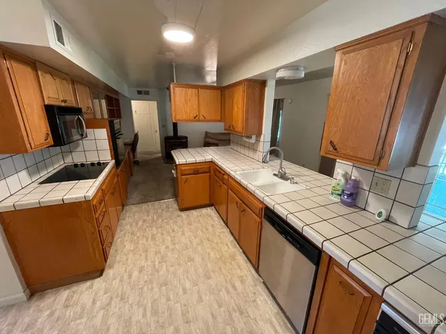 a living room with stainless steel appliances kitchen island granite countertop furniture a sink a rug and a window