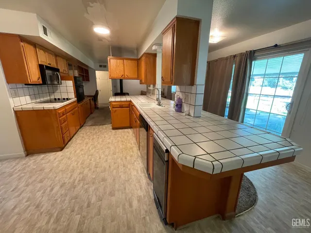 a kitchen with stainless steel appliances granite countertop a stove a sink dishwasher and a microwave with wooden floor