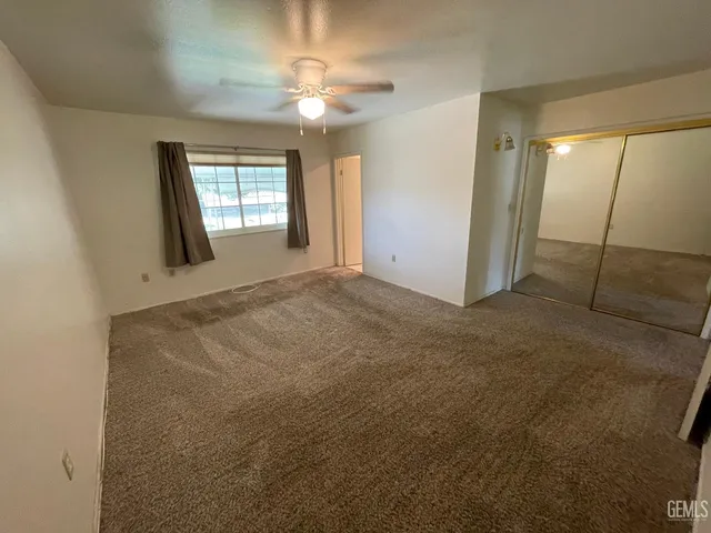 a view of an empty room with window and chandelier fan