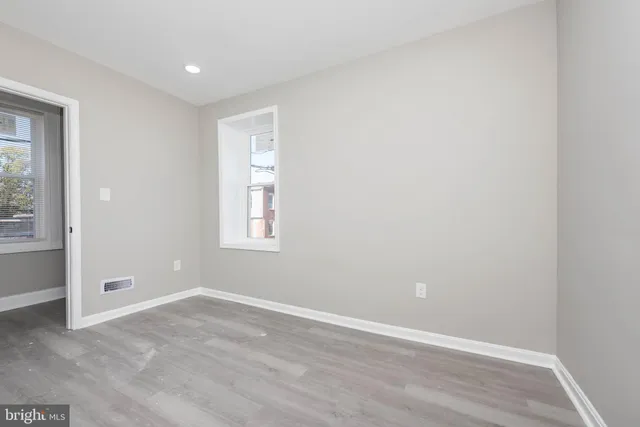 an empty room with wooden floor and windows
