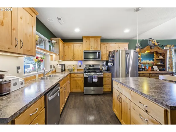 a kitchen with stainless steel appliances granite countertop a refrigerator a sink dishwasher and a stove with wooden floor