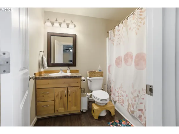 a bathroom with a granite countertop sink toilet a mirror and shower curtain