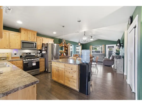 a kitchen with stainless steel appliances kitchen island granite countertop a stove top oven a sink a dining table and chairs