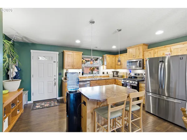 a kitchen with a refrigerator a stove a sink and a dining table with wooden floor