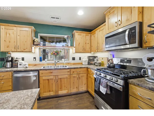 a kitchen with stainless steel appliances granite countertop a stove a sink and a microwave