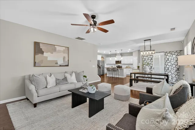 a living room with furniture kitchen view and a chandelier
