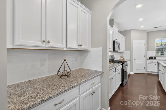 a kitchen with stainless steel appliances granite countertop a stove a sink and white cabinets
