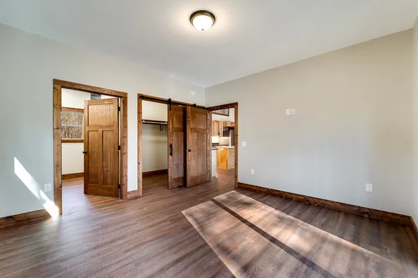 a view of an empty room with wooden floor and windows