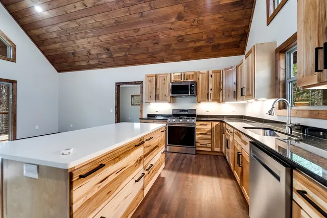 a kitchen with stainless steel appliances a stove top oven a sink a counter space and cabinets