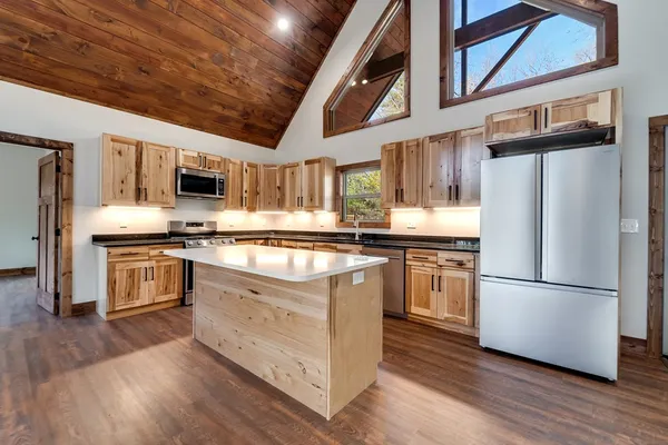 a kitchen with stainless steel appliances granite countertop a refrigerator a stove top oven a sink and dishwasher a oven with wooden floor