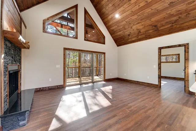 a view of an empty room with wooden floor and a fireplace