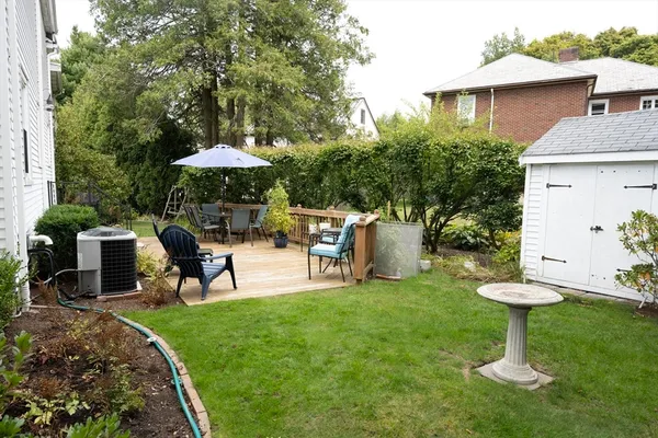 a view of a backyard with table and chairs potted plants and a large tree