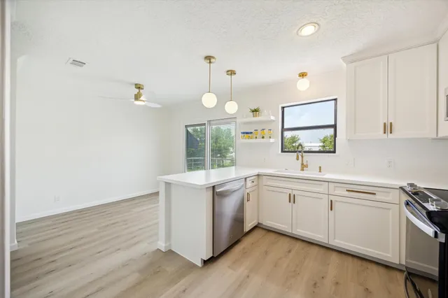 a kitchen with a sink cabinets wooden floor and stainless steel appliances