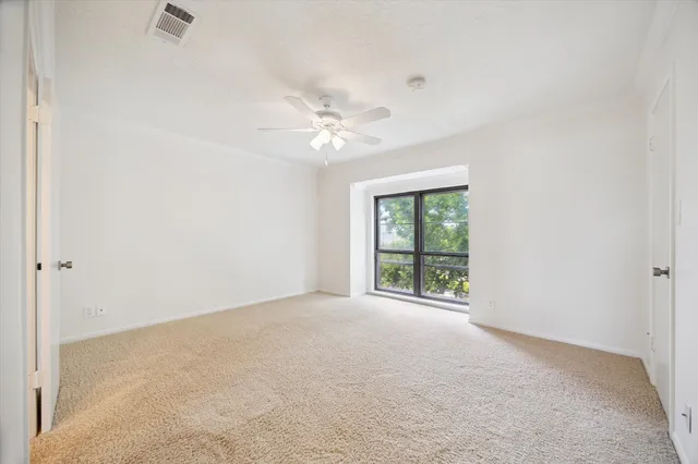 an empty room with windows and ceiling fan
