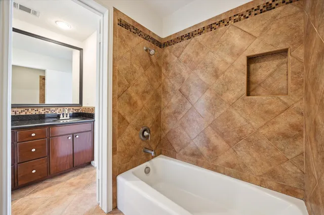 a bathroom with a granite countertop sink a mirror and a bathtub