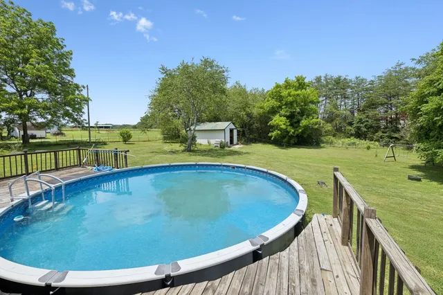 a view of a big yard with swimming pool and green space