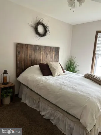 a bed sitting in a bedroom and dressers next to a window