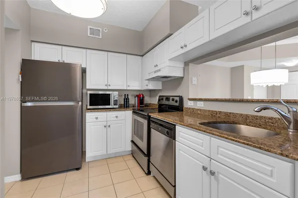 a kitchen with white cabinets and appliances