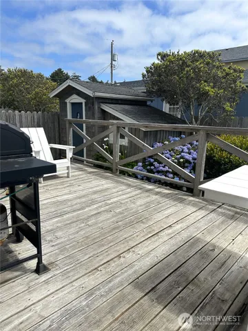 a view of a roof deck with table and chairs a barbeque with wooden floor and fence