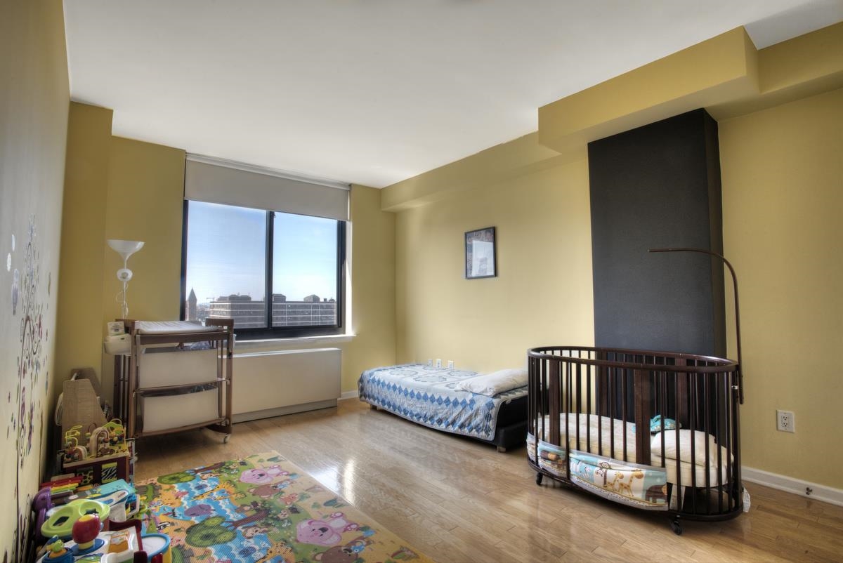 700 Grove Street, Unit 12J Jersey City, NJ 07310 - Photo 7 of 16 a bedroom with furniture and a baby crib