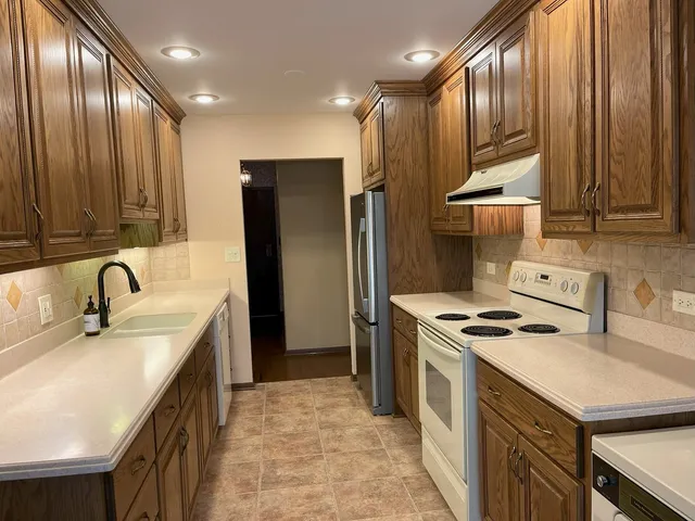 a kitchen with stainless steel appliances granite countertop a sink a stove and a refrigerator