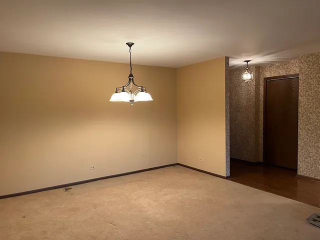 an empty room with a chandelier fan and wooden floor
