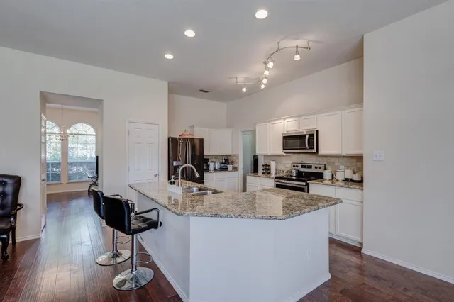 a kitchen with stainless steel appliances granite countertop a refrigerator a stove a sink a dining table and chairs