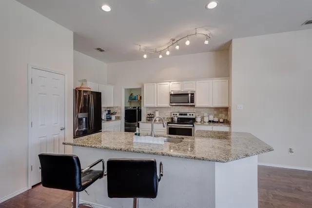 a kitchen with stainless steel appliances granite countertop a sink and stove a oven with wooden floor