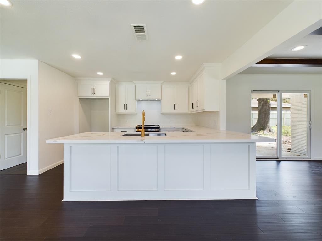 a kitchen with stainless steel appliances a sink a stove a refrigerator and white cabinets