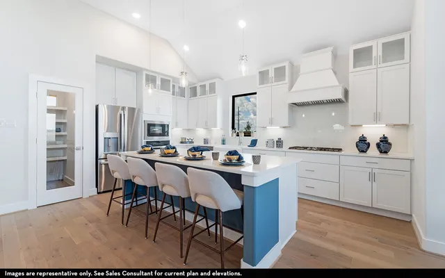 a kitchen with stainless steel appliances kitchen island granite countertop a table chairs sink and cabinets