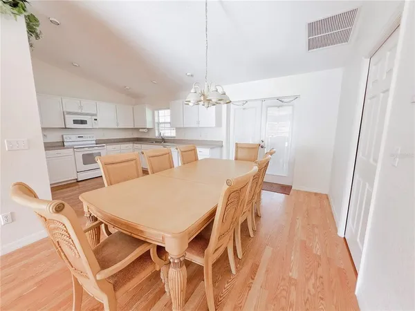 a dining room with furniture a chandelier and wooden floor